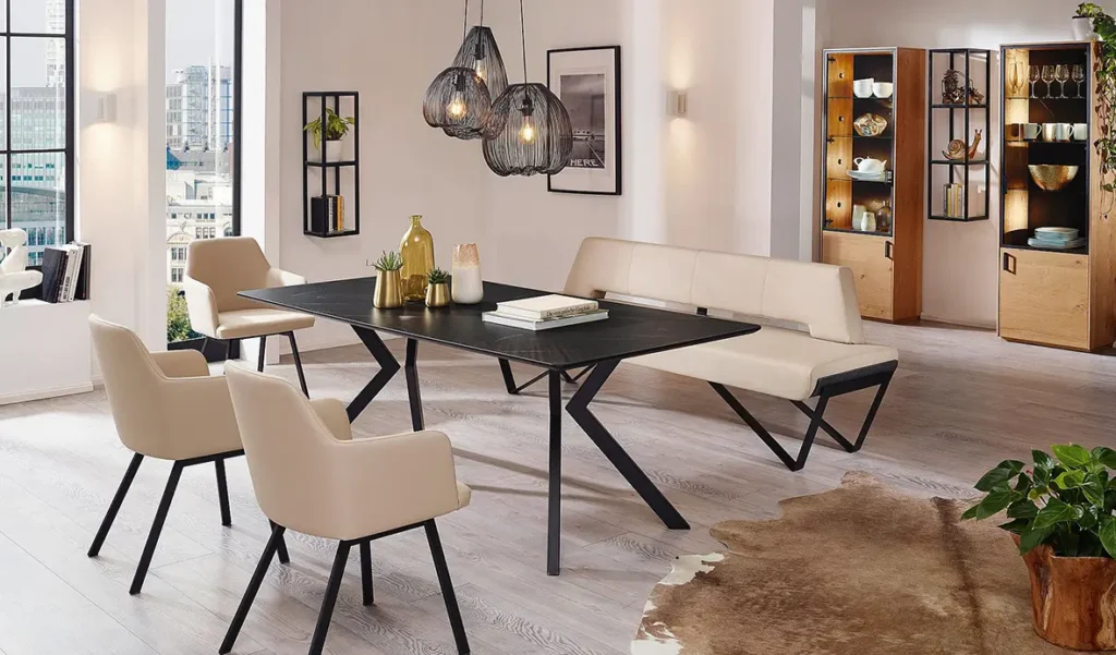 Wohnen - Esstisch aus dunklem Stein auf schwarzen Metallbeinen mit einer weißen Lederbank und drei Stühlen auf schwarzen Metallbeinen